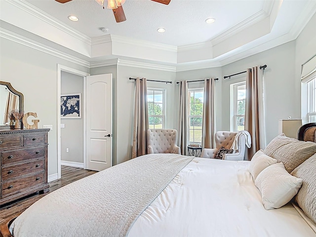 bedroom with ornamental molding, recessed lighting, dark wood-style flooring, and a tray ceiling