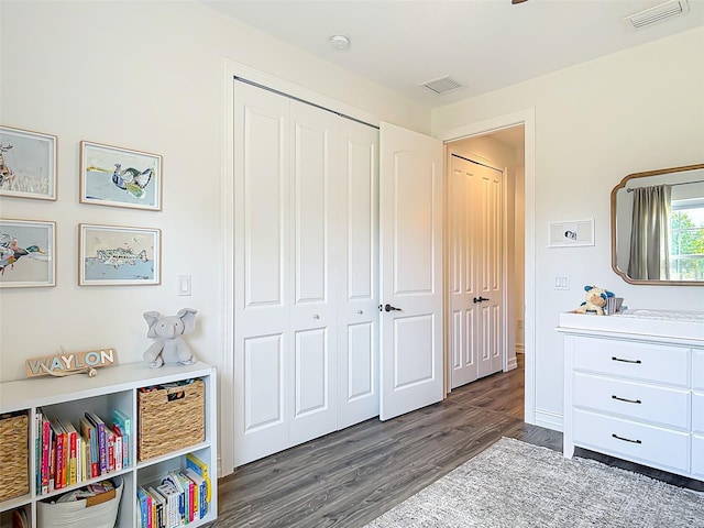 bedroom with wood finished floors, visible vents, and a closet