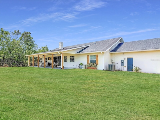 back of house with ceiling fan, a yard, cooling unit, a chimney, and stucco siding