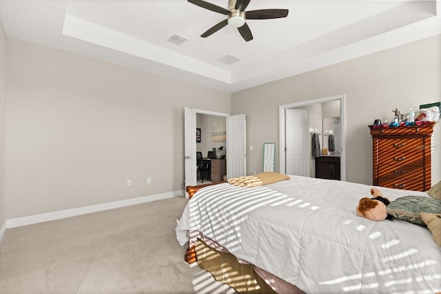 bedroom with carpet, a raised ceiling, baseboards, connected bathroom, and a ceiling fan
