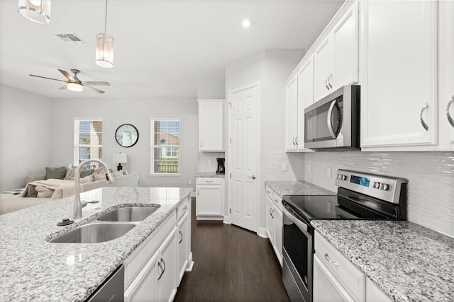 kitchen featuring appliances with stainless steel finishes, a sink, dark wood-style floors, decorative backsplash, and white cabinetry