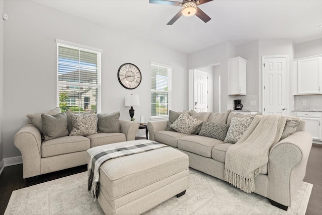 living area with light wood finished floors, a ceiling fan, and baseboards
