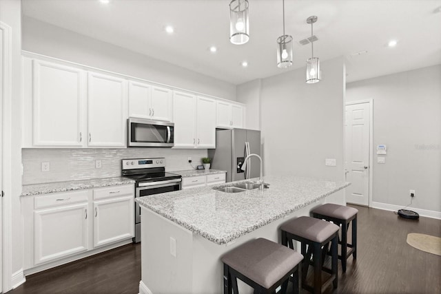 kitchen with appliances with stainless steel finishes, a sink, dark wood-style floors, a kitchen island with sink, and recessed lighting
