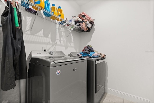 laundry area featuring independent washer and dryer, baseboards, and light tile patterned floors