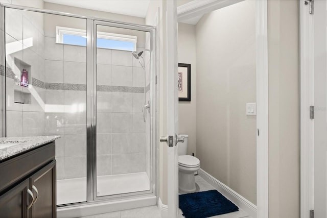 bathroom featuring a shower stall, toilet, vanity, tile patterned floors, and baseboards