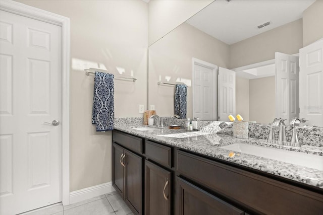bathroom featuring tile patterned flooring, baseboards, and double vanity