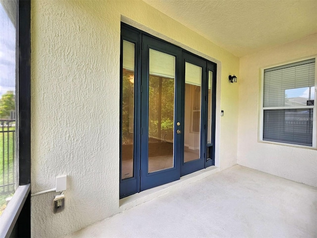 view of exterior entry featuring french doors, stucco siding, and a patio
