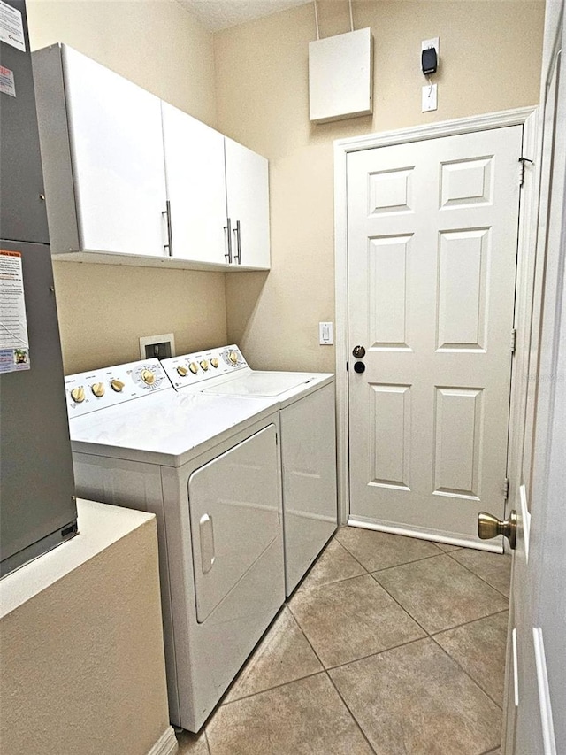 clothes washing area with independent washer and dryer, cabinet space, and light tile patterned floors