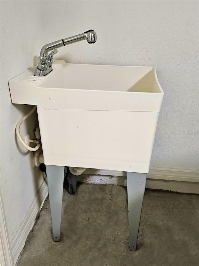 detailed view of unfinished concrete flooring, a sink, and baseboards
