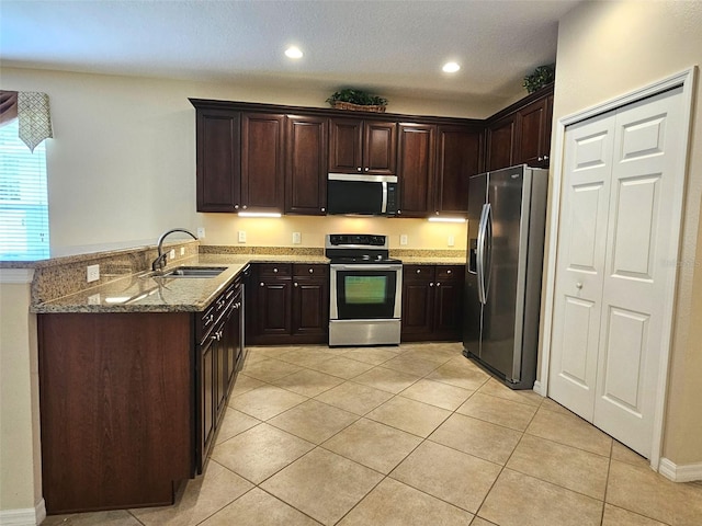 3506 Creswick Cir, Orlando, FL 32829 - kitchen with stainless steel appliances, dark brown cabinetry, a peninsula, light stone countertops, and light tile patterned floors