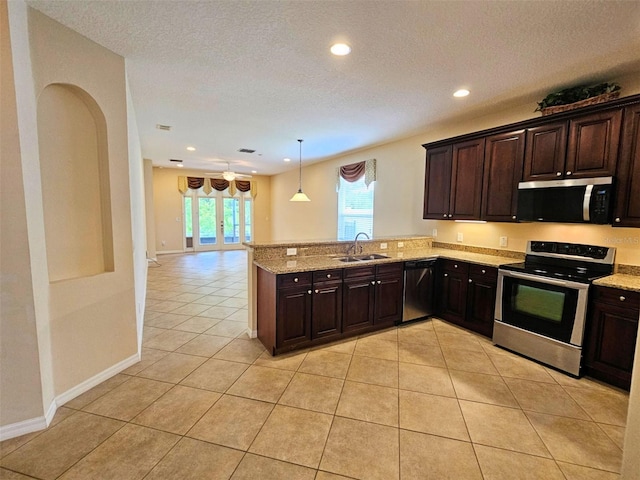 3506 Creswick Cir, Orlando, FL 32829 - kitchen with stainless steel appliances, light tile patterned floors, dark brown cabinetry, recessed lighting, and a peninsula
