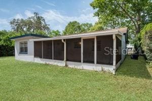 1051 Arden St, Longwood, FL 32750 - back of house featuring a sunroom and a lawn