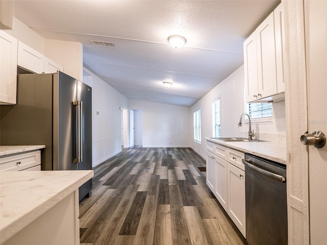 kitchen with stainless steel appliances, a sink, white cabinetry, visible vents, and dark wood-type flooring