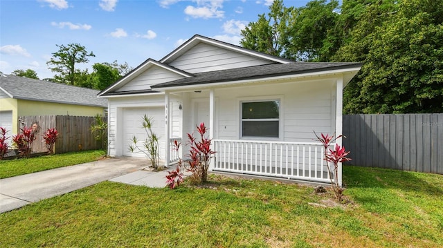 view of front of property featuring a front lawn, driveway, a garage, and fence
