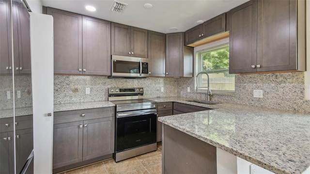 kitchen with a sink, decorative backsplash, visible vents, light stone counters, and appliances with stainless steel finishes