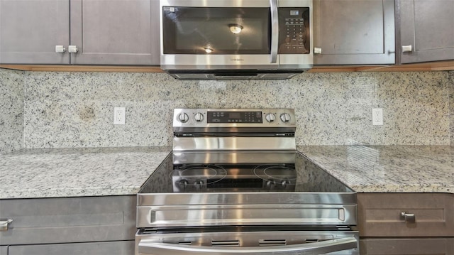 kitchen with light stone counters, appliances with stainless steel finishes, and decorative backsplash