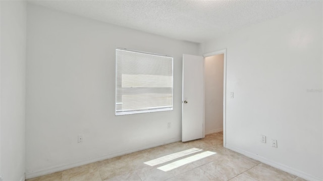 unfurnished room featuring a textured ceiling and baseboards