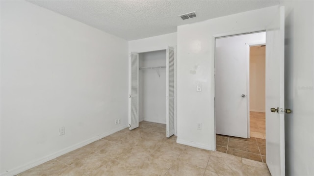 unfurnished bedroom with a closet, visible vents, and a textured ceiling