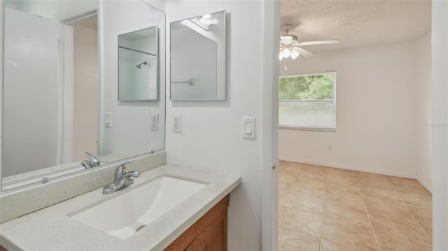 bathroom featuring tile patterned floors, ceiling fan, vanity, baseboards, and a textured ceiling
