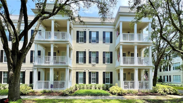 back of house featuring ceiling fan, stucco siding, and a balcony