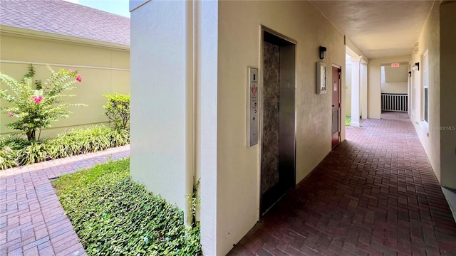 hall with elevator and brick floor