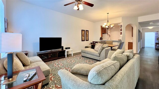 living area featuring arched walkways, baseboards, and ceiling fan with notable chandelier