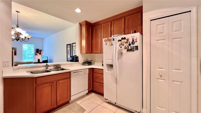 kitchen with an inviting chandelier, a sink, brown cabinets, and white appliances