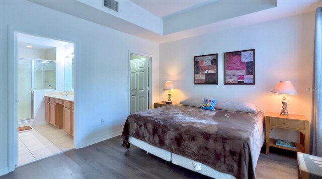 bedroom with light wood-style floors, baseboards, connected bathroom, and visible vents