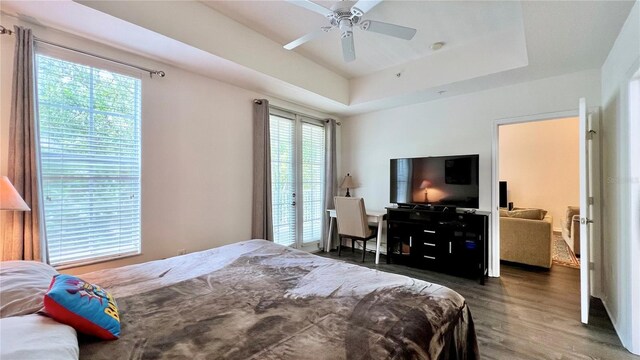 bedroom with a tray ceiling, ceiling fan, and wood finished floors