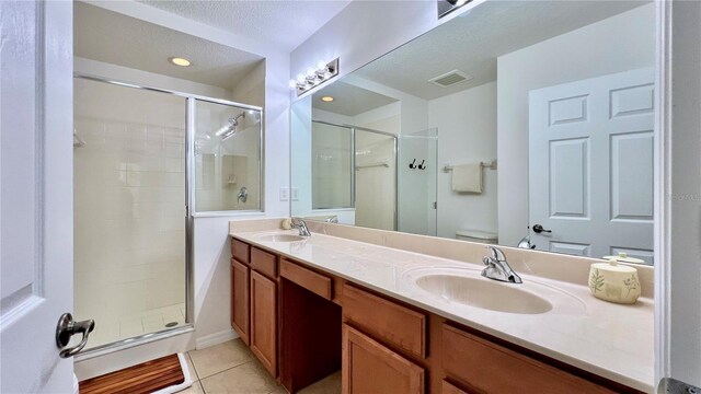 bathroom featuring a sink, tile patterned flooring, a stall shower, and visible vents