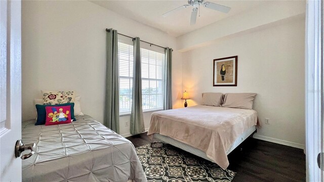 bedroom featuring baseboards, dark wood finished floors, ceiling fan, and multiple windows