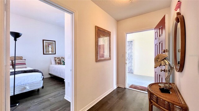 corridor featuring baseboards and dark wood finished floors