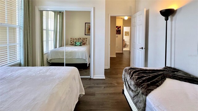 bedroom featuring baseboards, dark wood-style floors, and a closet