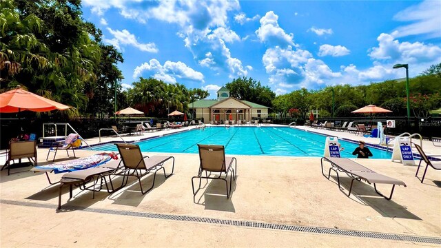 community pool with a patio and fence