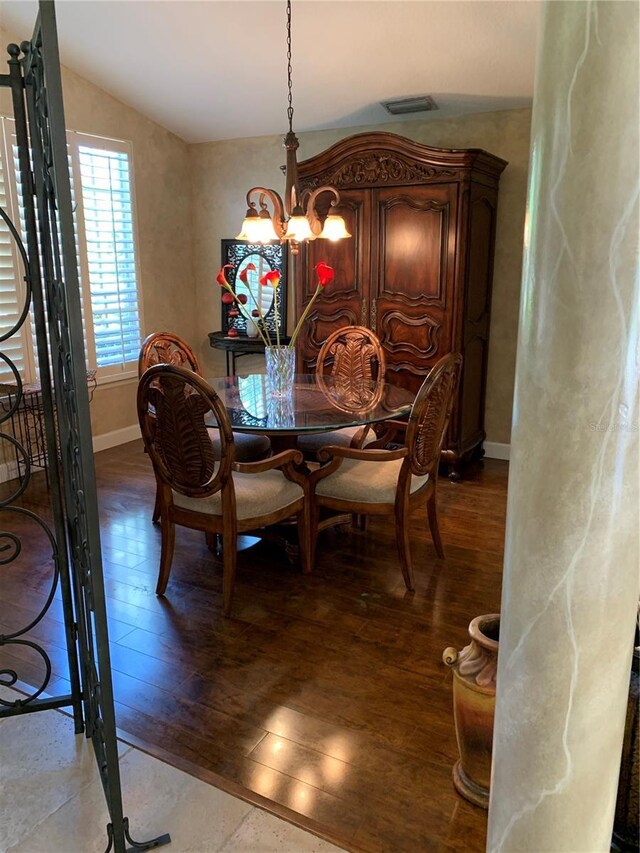 dining room featuring vaulted ceiling, visible vents, a chandelier, and dark wood finished floors