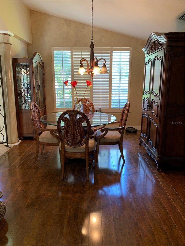 dining room featuring lofted ceiling, a chandelier, visible vents, and dark wood finished floors