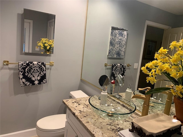 bathroom with baseboards, toilet, and vanity