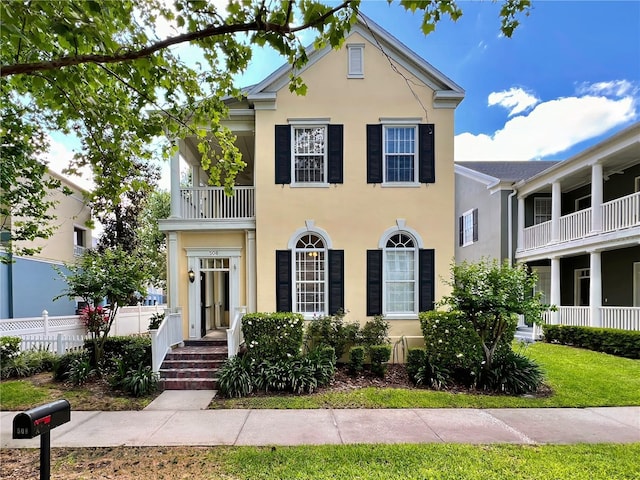 traditional-style house with stucco siding, fence, and a balcony
