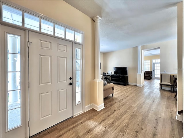 entrance foyer with baseboards, light wood-style flooring, and ornate columns