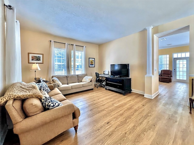 living room featuring baseboards, decorative columns, a wealth of natural light, and light wood-style floors