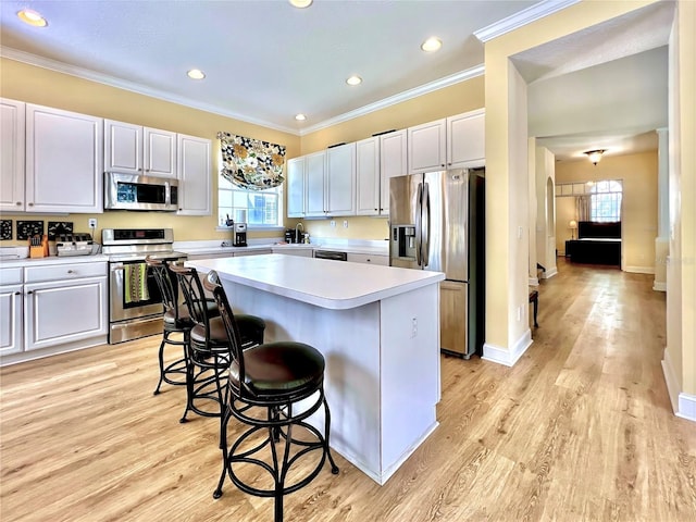 kitchen with a breakfast bar area, appliances with stainless steel finishes, a kitchen island, light countertops, and a wealth of natural light