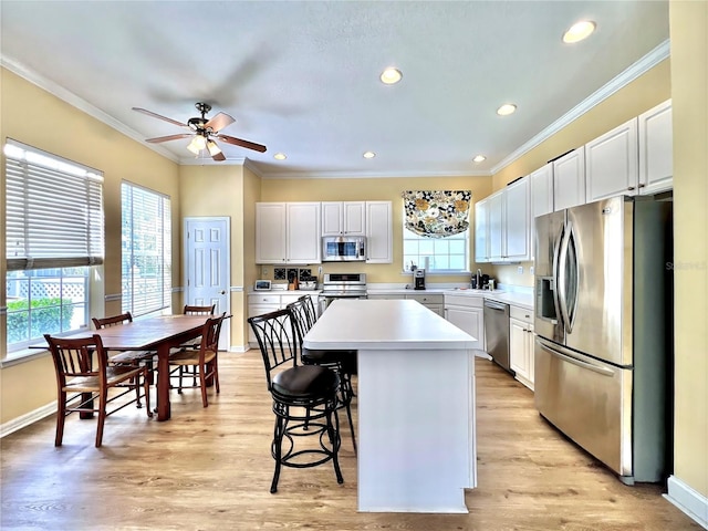 kitchen with a center island, ornamental molding, stainless steel appliances, and light countertops