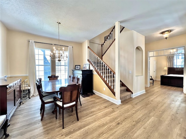 dining area with a textured ceiling, light wood-style flooring, and stairs
