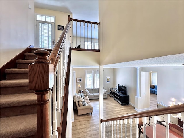 staircase with a towering ceiling, baseboards, wood finished floors, and plenty of natural light