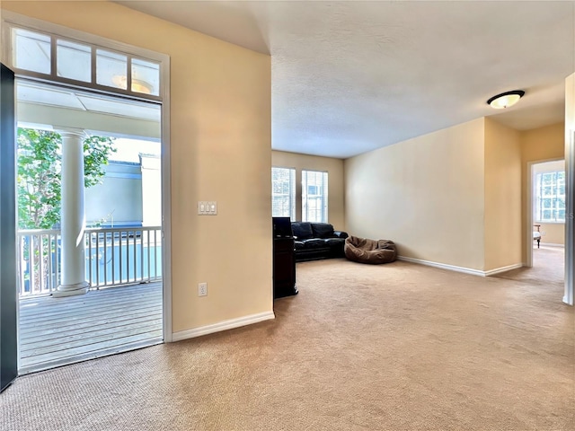 interior space featuring decorative columns, carpet, and baseboards