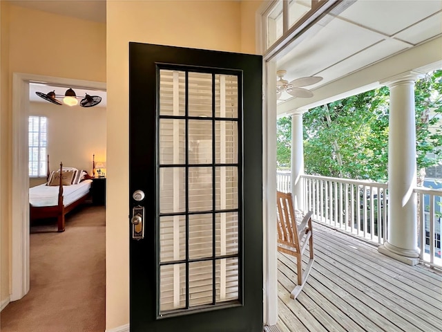 doorway featuring a ceiling fan and decorative columns