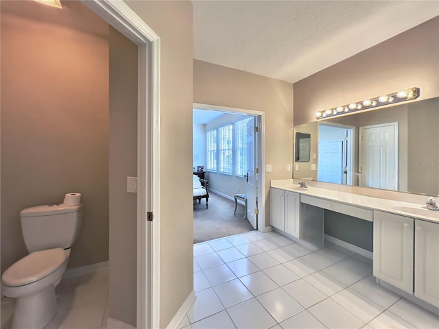 bathroom with a sink, tile patterned floors, toilet, double vanity, and baseboards