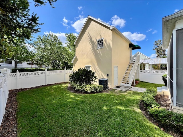 exterior space featuring stucco siding, a yard, stairs, and a fenced backyard