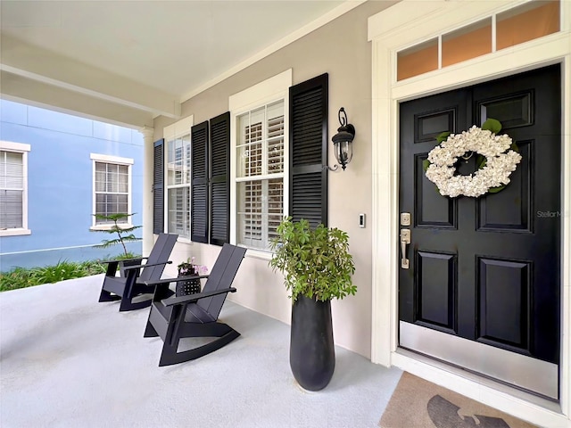 view of exterior entry with covered porch and stucco siding