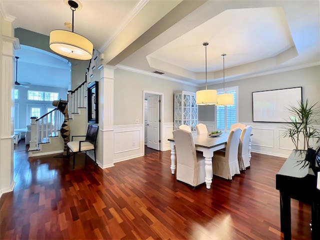dining area with wood finished floors, a tray ceiling, stairs, and a decorative wall